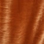 Close-up of copper orange crystal velvet fabric laid flat, showing the soft plush texture, tonal shading and light-catching sheen across the surface.