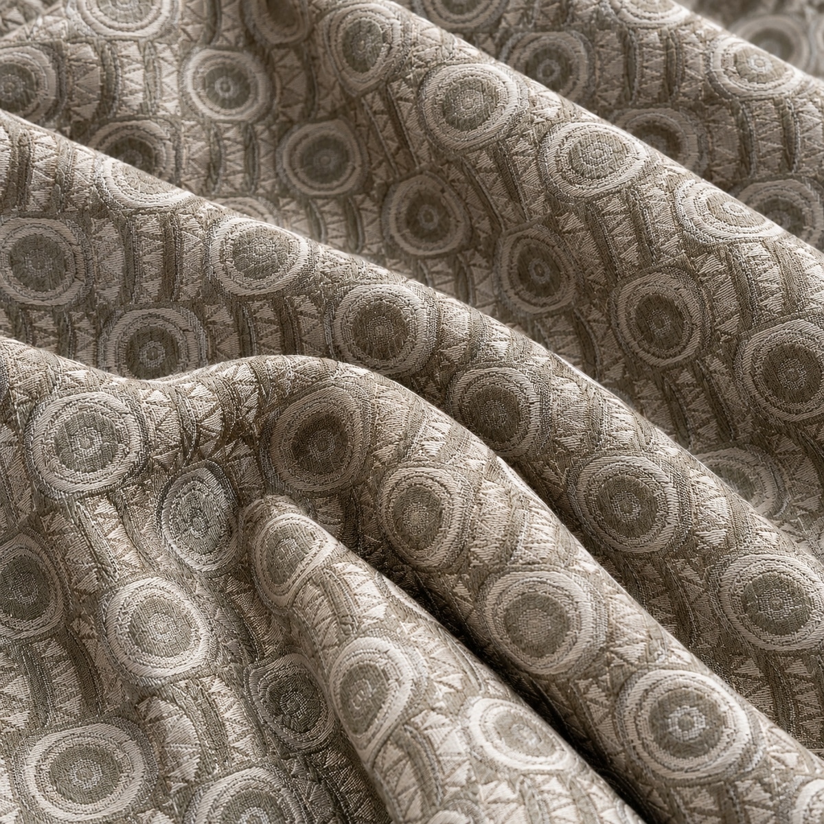 SKT1005-04 Sage green and silver grey jacquard fabric arranged in broad overlapping folds, showing raised concentric circles alternating with narrow vertical bands of angular geometric motifs.