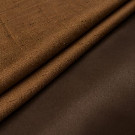 Two folds of copper-brown Dupion silk showing the slubbed, lightly reflective right side and contrasting smooth dark-brown reverse.