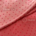 Folded pink silk jacquard revealing its light pink right side and deeper reddish-pink reverse, both with small woven dot motifs; white labels identify “Right Side” and “Reverse Side”.