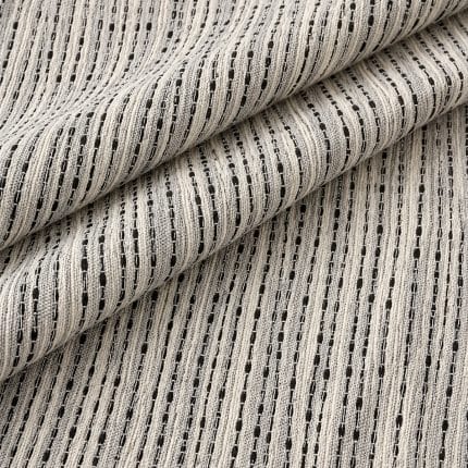 Close-up of off-white and midnight blue textured fabric laid in broad diagonal folds, revealing the repeated linear pattern of raised pale threads and narrow dark stripes.