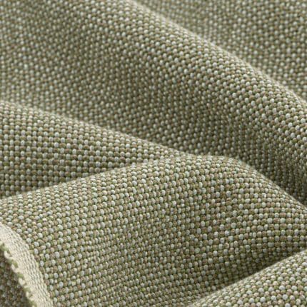 Folded edge of textured sage green, ivory and beige linen fabric, showing a pale woven selvedge and the thick, interlaced threads on the main surface.