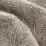 Close-up of ivory chiffon showing overlapping feather-like motifs formed by raised champagne-toned embroidery and tiny matching sequins.