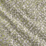 Close-up of silver-grey silk jacquard laid flat, showing densely repeating irregular circular motifs with lime green centres and grey-green outlines.