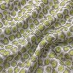Silver-grey silk jacquard in diagonal folds, showing lime green circular motifs with grey-green outlines and a soft, textured surface.